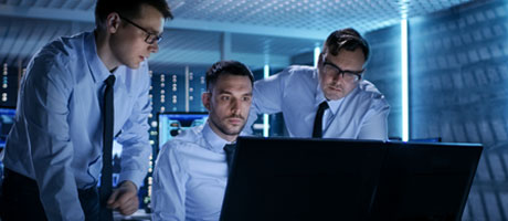 3 guys around a computer screen in a server room